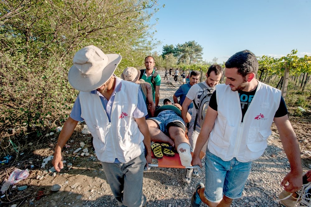 Doctor Hasan Abuhamdam (left) and translator Mohammed Ghareeb (right), transport a patient, together with his friends in Idomeni, Greece. MSF doctor, Hasan Abuhamdam, suspects he might have a broken bone. He is later transferred to a Red Cross team who take him to hospital for further treatment. Photo: Borja Ruiz Rodriguez