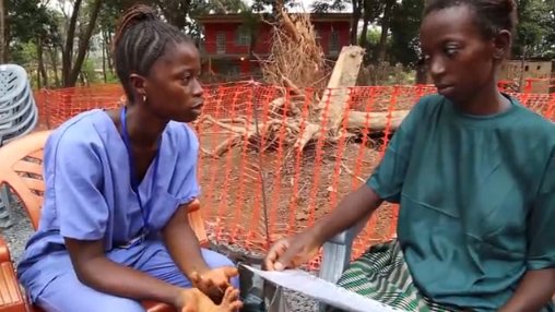 An MSF team member hugs Adama as they arrive in her neighbourhood to demonstrate to the community that she is no longer infectious.