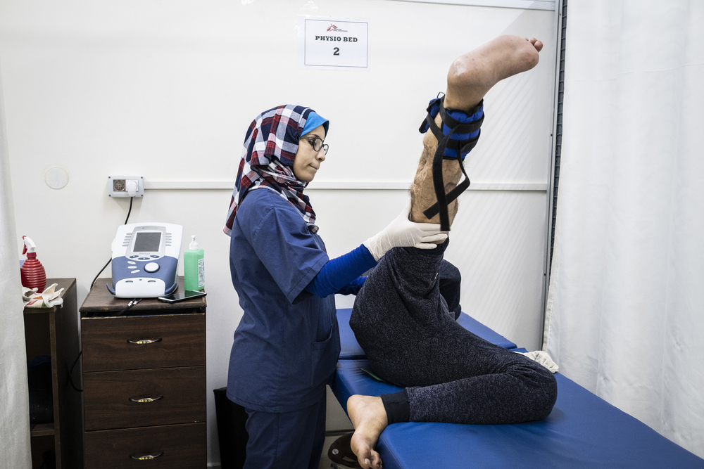 Sabrine Wadi, a physiotherapist working with MSF at Al Awda hospital in northern Gaza, assists a patient with his physiotherapy exercises.