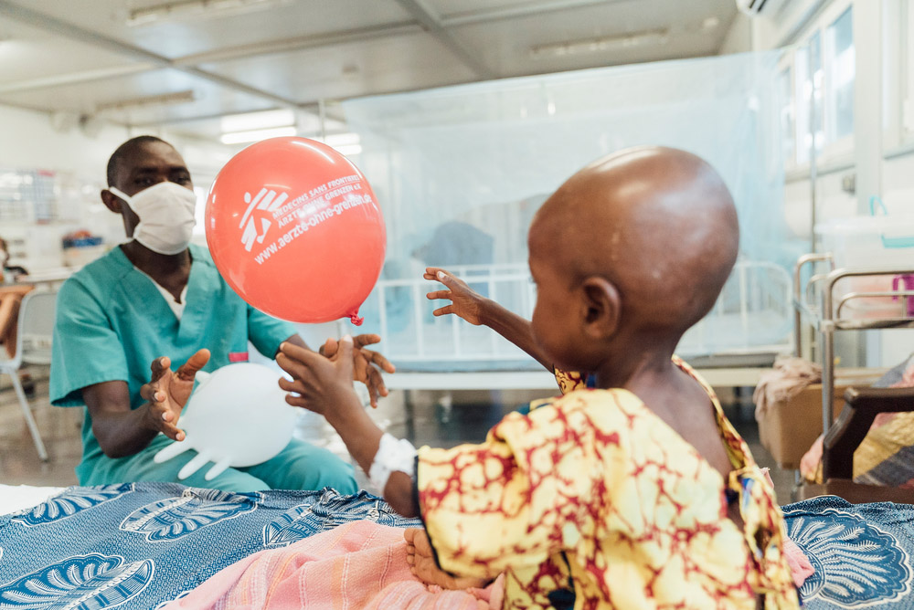 A picture of a child holding a balloon at Kenema Hospital with an MSF staff member.