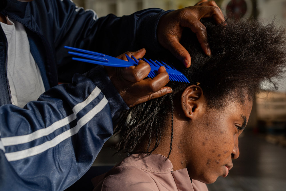 A female survivor braids another woman’s hair