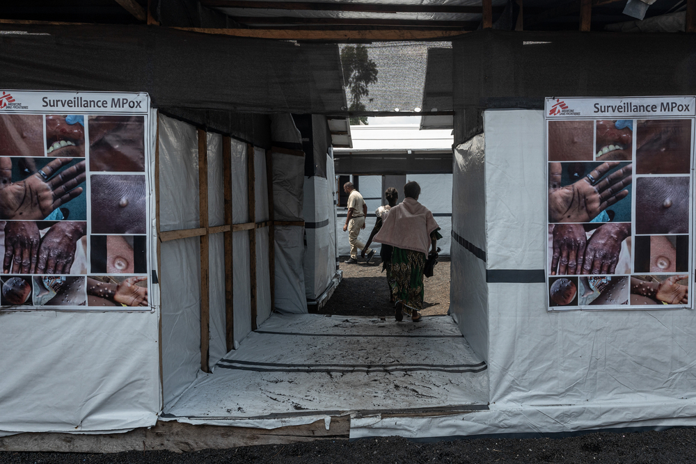 People enter a canvas and wood MSF mobile clinic.