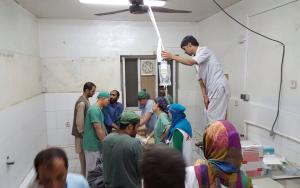 surgery and trauma teams work on a patient while an assistant holds the IV bags above their heads