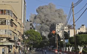 People run away from the vicinity of Al-Sharouk tower as it collapses after being hit by an Israeli air strike, in Gaza City, on May 12, 2021. 
