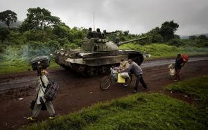 A tank moves towards the frontlines as people carry their belongings as they flee fighting on Monday, Oct. 27, 2008 near Kibumba in eastern Congo. Government forces are forced to retreat as they are being pushed closer to Goma by rebels of renegade Gen. Laurent Nkunda. 