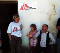 Mobile clinic in Kraijc Kosovo. MSF worker in conversation with man and child. 