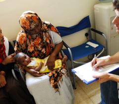 Doctor John Hart in consultation with a Somali woman and her baby suffering from a fungal skin infection and the clinic run by MSF near the centres for migrants and asylum seekers in Malta. A cultural mediator translates into the patient's language.