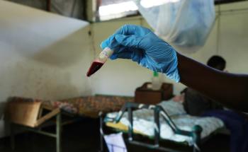 A gloved nurse holds a vial of blood to test for snakebites