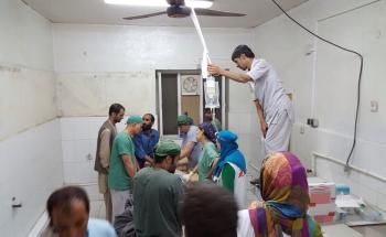 surgery and trauma teams work on a patient while an assistant holds the IV bags above their heads