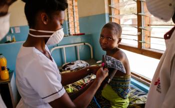 Deborah, MSF Nurse Mentor, is conducting a physical examination for Esther, an advanced HIV patient.
