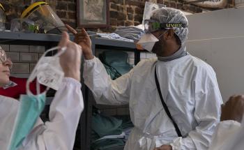 Cultural mediators and medical staff getting dressed with PPE before the medical round. 