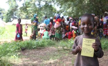 A child holding up their vaccination card