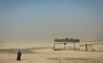 A woman walks in the desert, not far from her house.