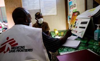 A picture of an MSF healthworker showing a patient TB symptom chart in Papua New Guinea