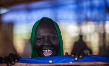 A woman smiling at the camera in Bambasi Camp