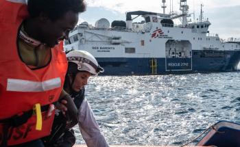 MSF Cultural Mediator Nejma helps a survivor on one of the Rigid Hull Inflatable Boats