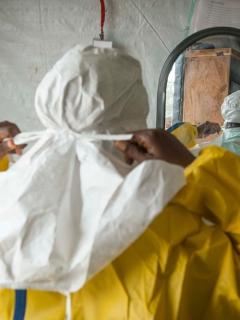A staff worker gears up in PPE to work with Ebola patients