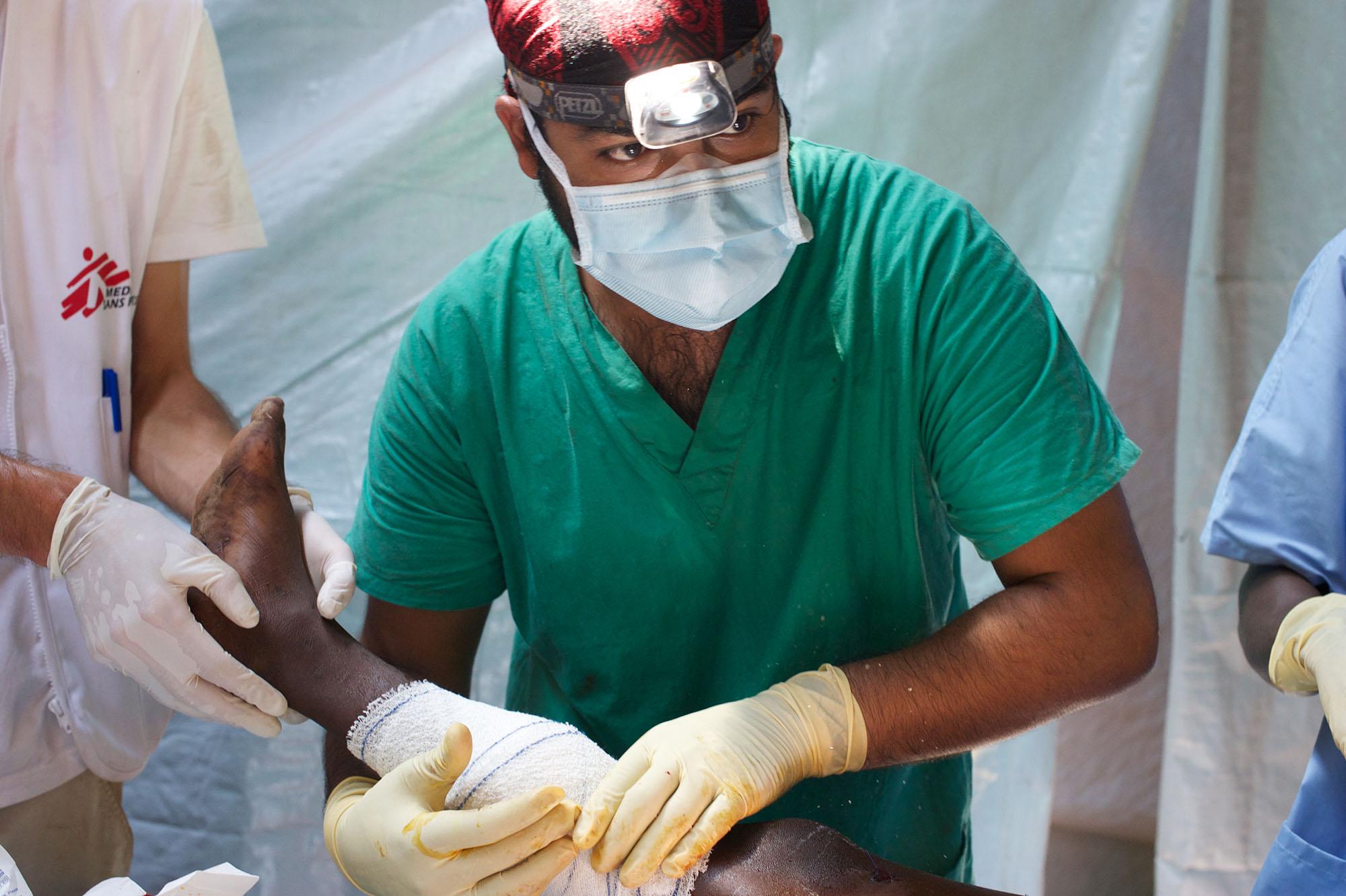Tahir Wissanji, MSF Doctor, putting on dressing on the leg of a 10 year old injured boy in the Mpoko camp MSF clinic at Bangui airport.