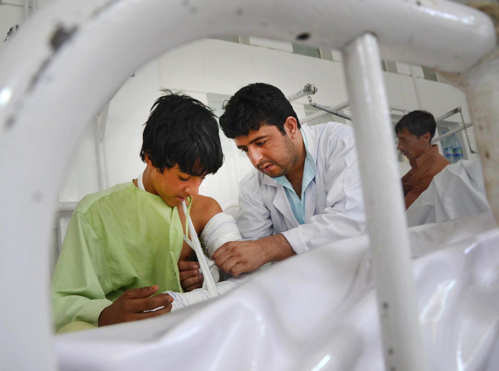 MSF physiotherapist Baryali Baloch fixes bandages on the arm of a patient 