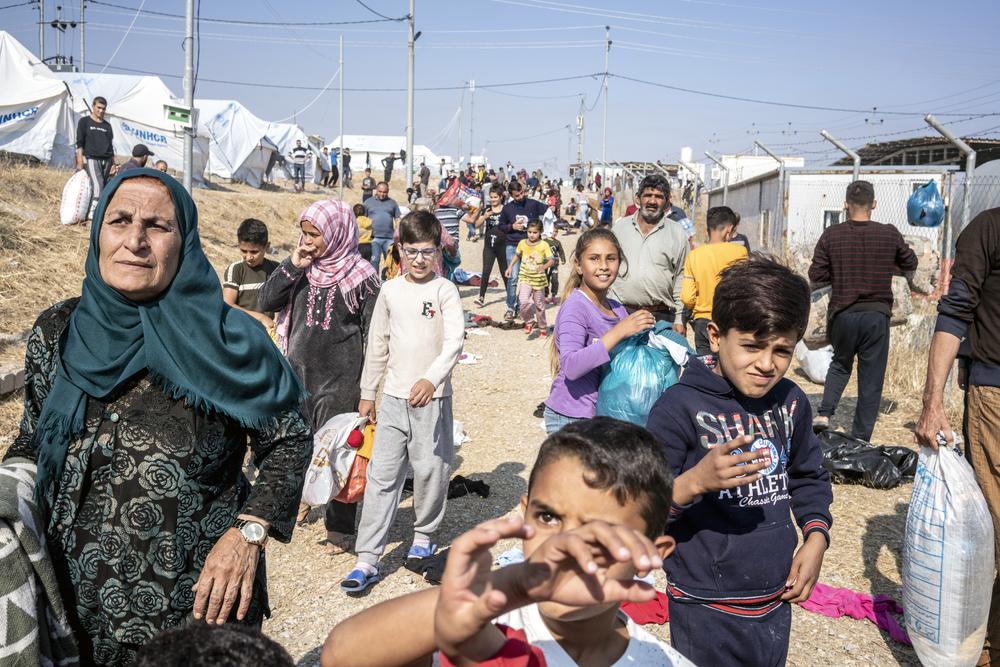 Syrian Kurdish refugees gather to receive winter clothes being distributed by inside the Bardarash refugee camp in Iraqi-Kurdistan