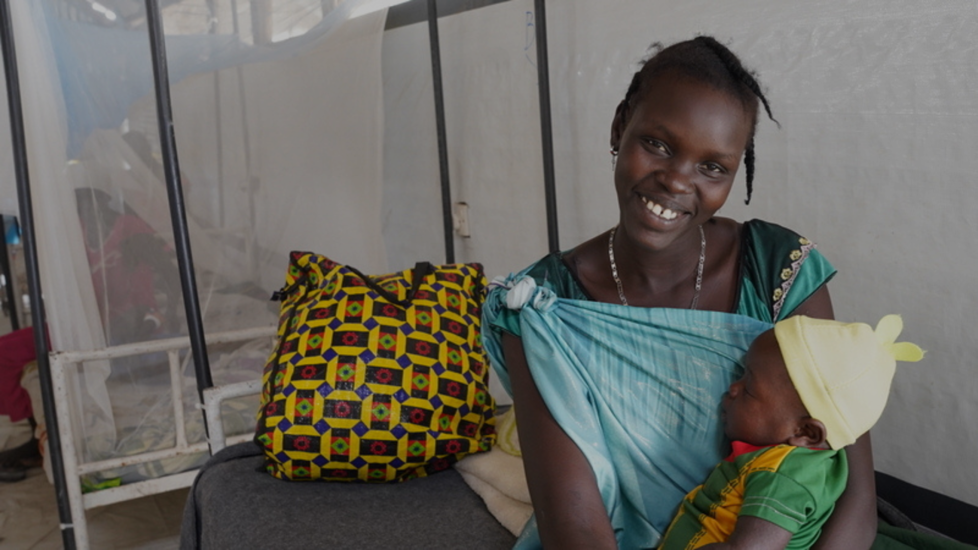 Myamach smiles as she holds her 5-month-old son Makuach who is under treatment at the measles isolation centre run by MSF in Lankien, Nyirol County in Jonglei state, South Sudan. Page