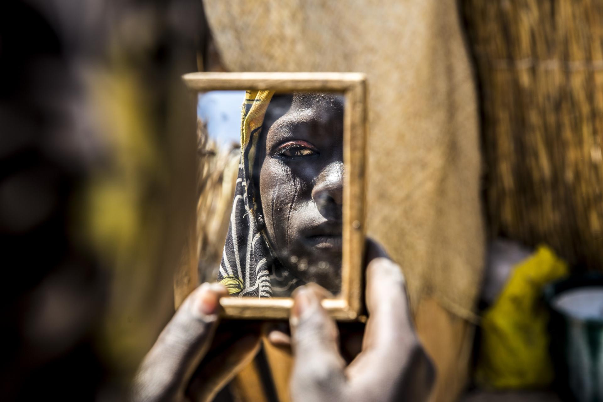 A women starring back at her reflection in a handheld mirror
