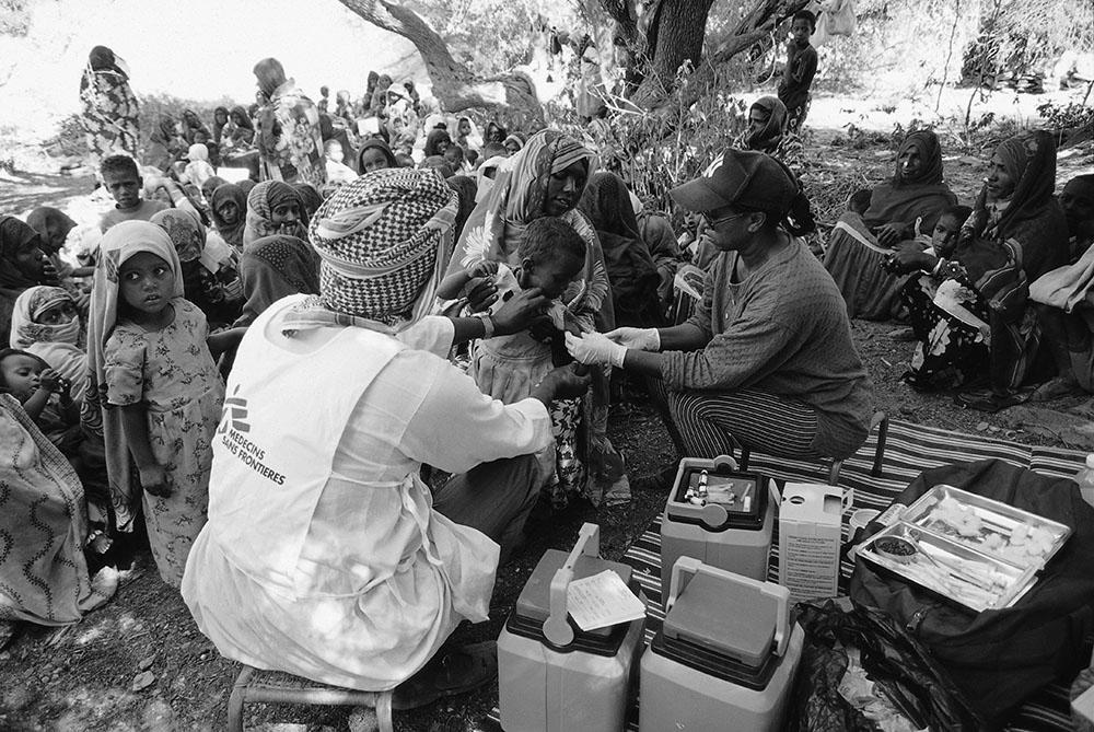 Vaccination campaign under a tree in a refugee camp in the mountains.