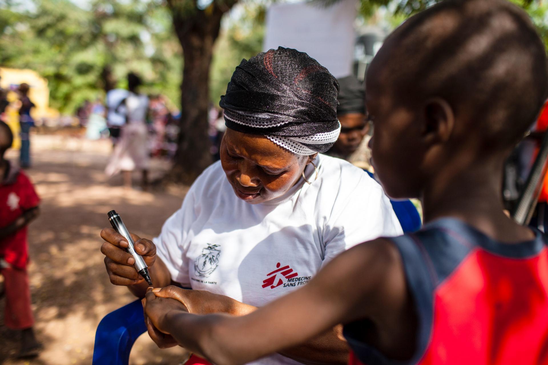 A picture of an MSF team member marking a vaccinated girl during a vaccination day