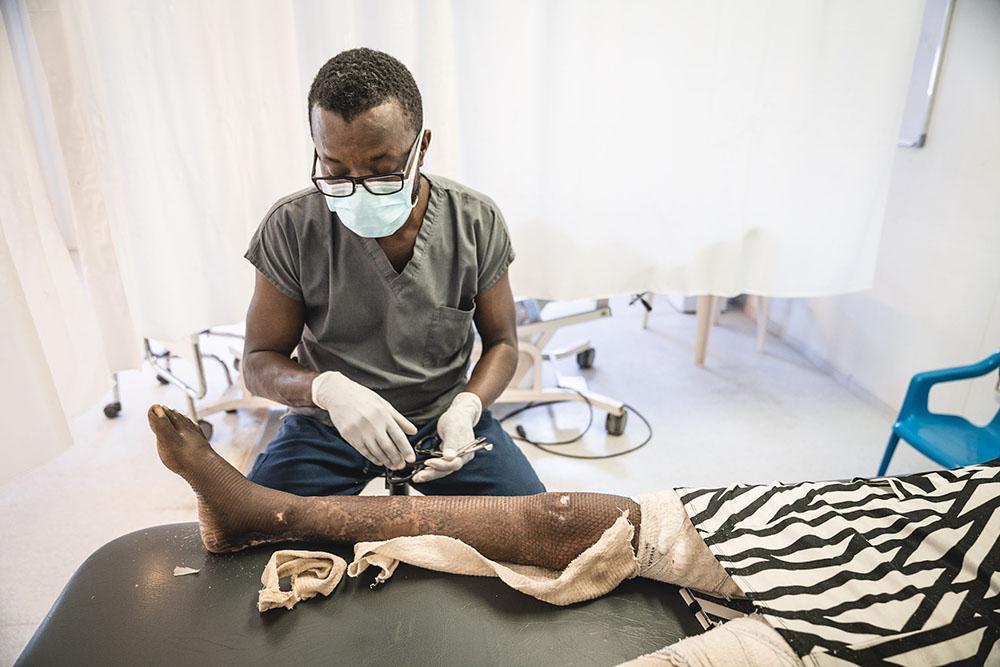 MSF staff cleaning a skin graft for a patient who suffered a severe burn on her leg.  in October 2021.