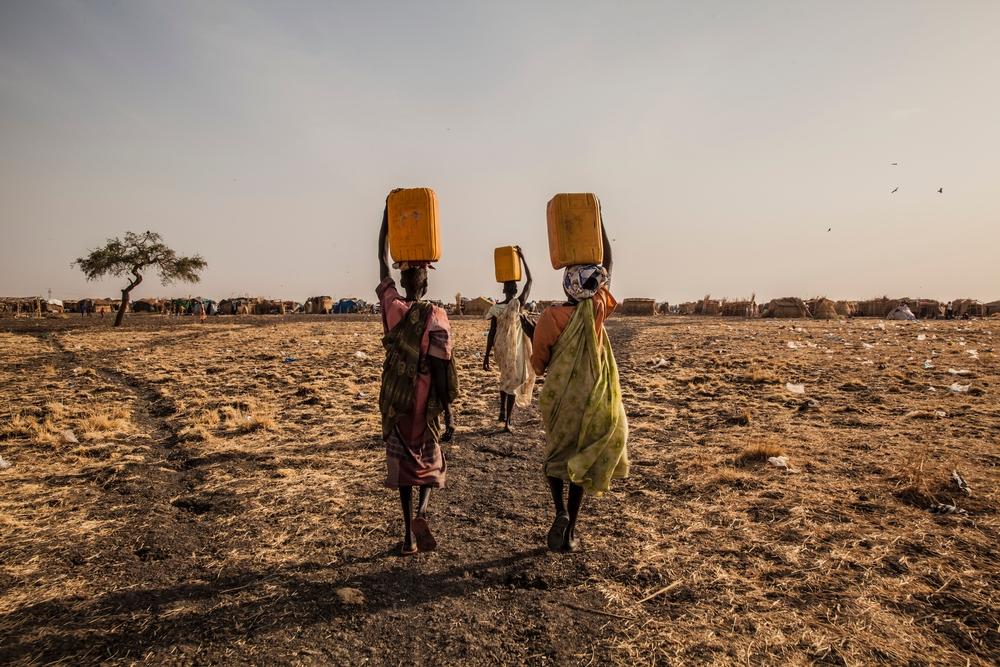 Three women carrying water in a camp for displaced people in Melut, South Sudan. 