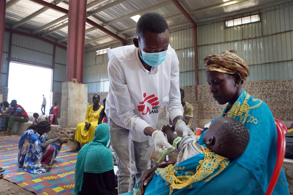 An MSF nurse aide performs the MUAC measurement test on a child at the MSF mobile refugee clinic in Sudan