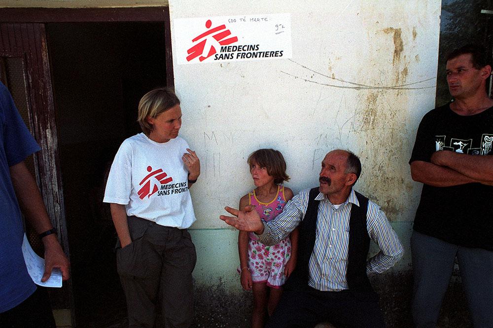 Mobile clinic in Kraijc Kosovo. MSF worker in conversation with man and child. 