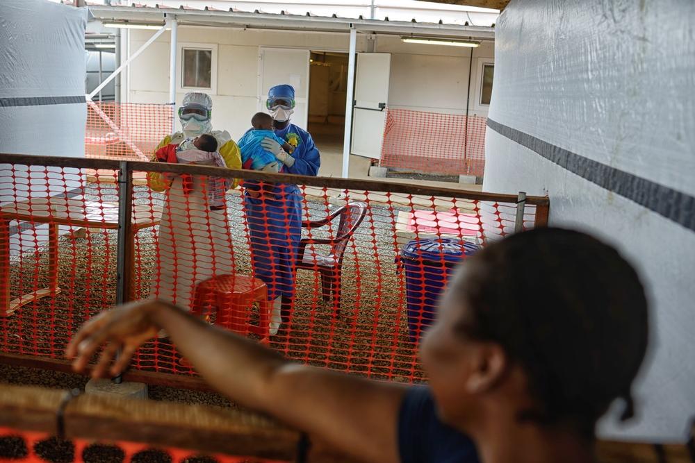 Two health workers holding children infected by the Ebola virus