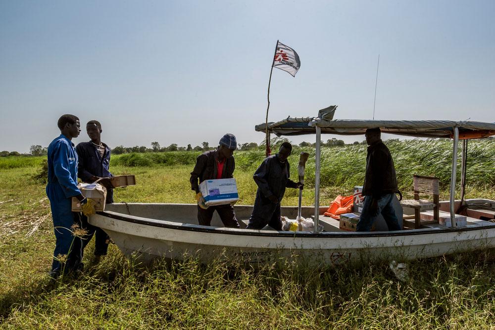 Beside the small airstrip, local men load cargo onto a MSF boat that will transport the supplies to the Old Fangak hospital. 