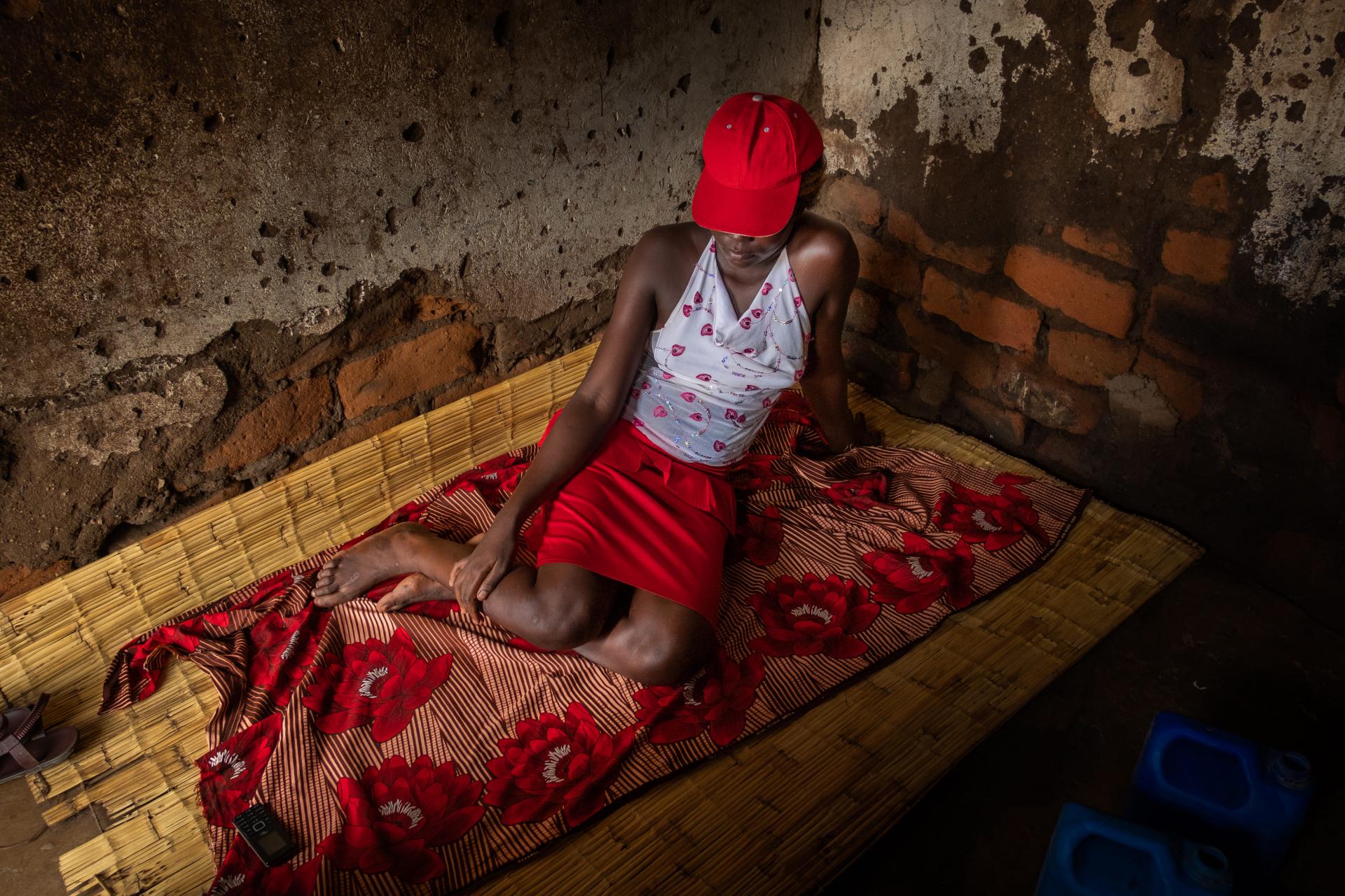 A sex worker on grass mat in a rented room where she lives that is also used for clients in a compound in Nsanje