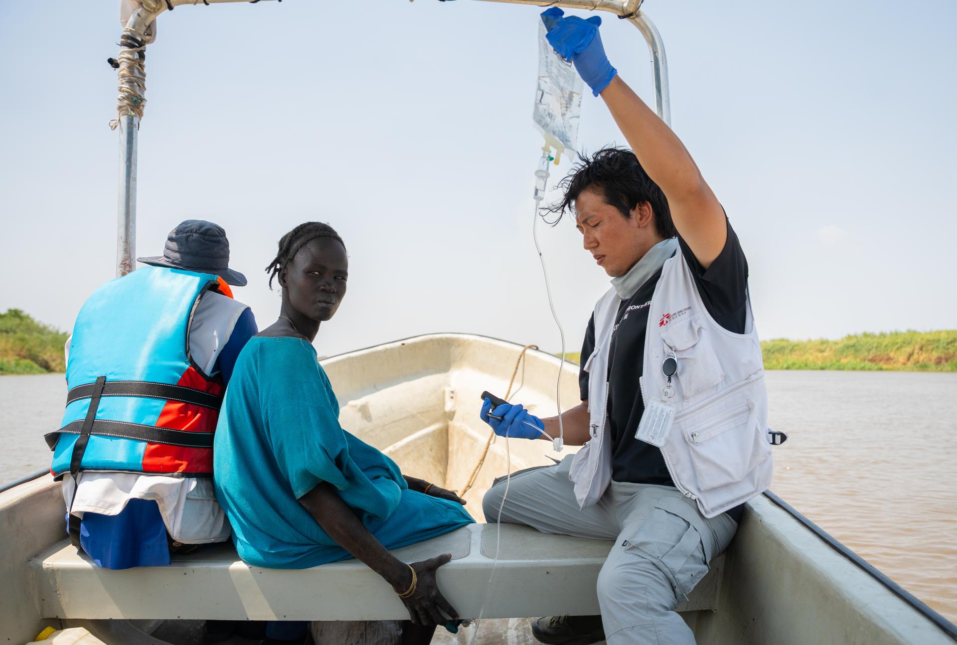 MSF staff member Joon Hyuk holds an IV drip for a patient being referred to Chuil primary healthcare centre , as the patient is transported for further treatment from a mobile clinic in Yakuach.