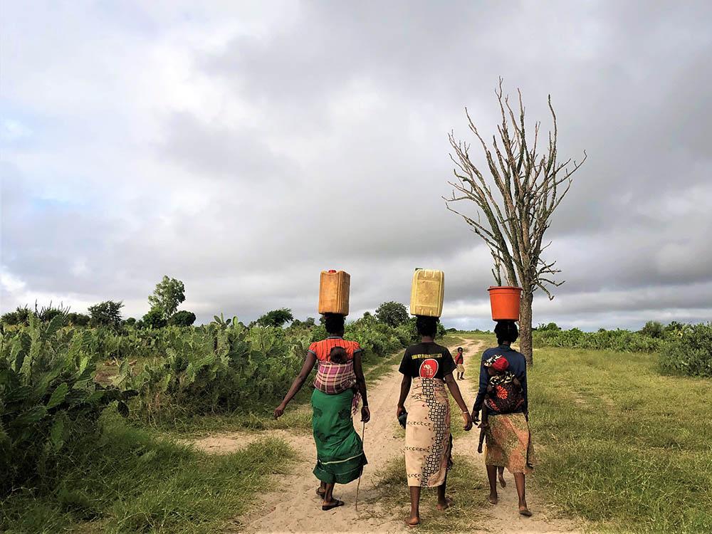 Three women return to their village after collecting water from a water distribution organized by MSF teams in the village of Fenoiva. 