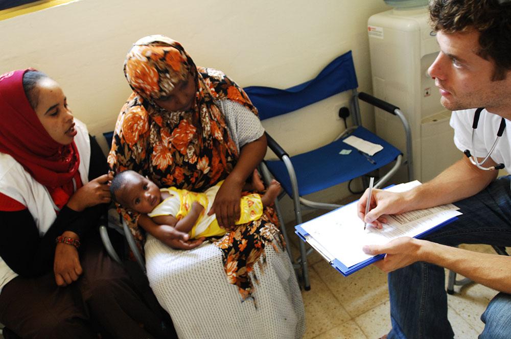 Doctor John Hart in consultation with a Somali woman and her baby suffering from a fungal skin infection and the clinic run by MSF near the centres for migrants and asylum seekers in Malta. A cultural mediator translates into the patient's language.