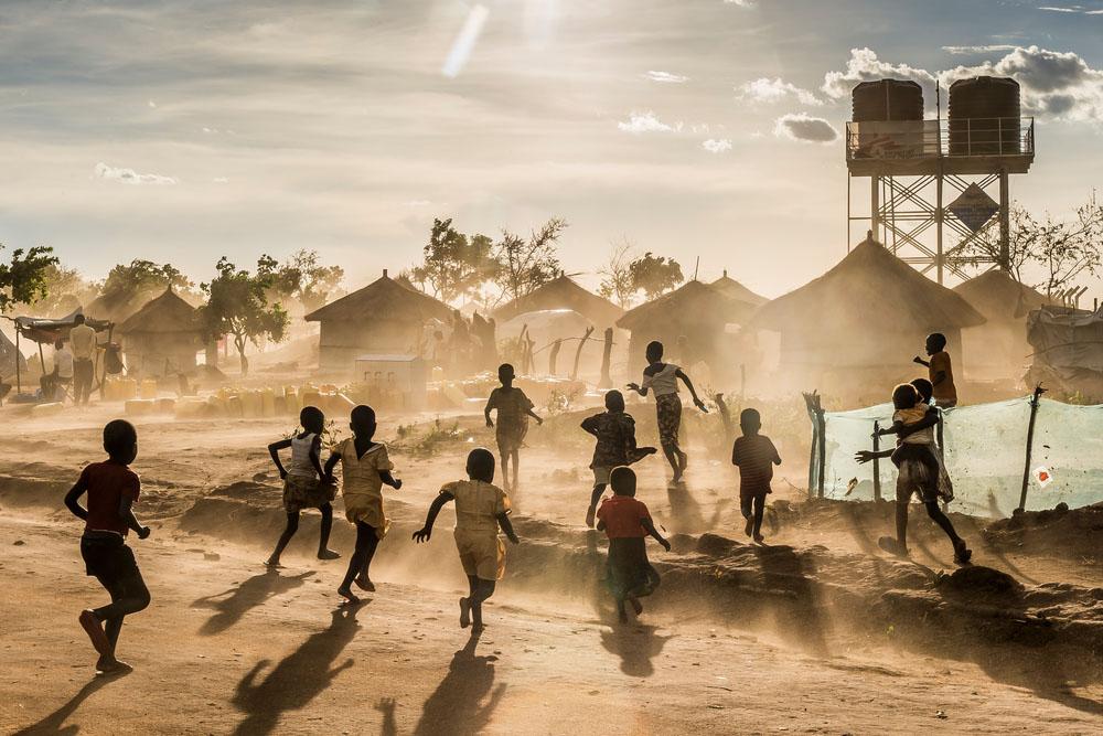 Children are playing in the Bidibidi camp. On the background we can see some shelters and the water tank provide by MSF.