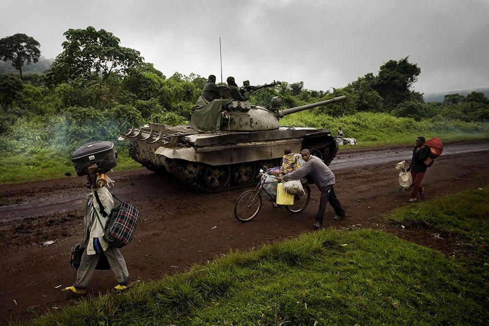 A tank moves towards the frontlines as people carry their belongings as they flee fighting on Monday, Oct. 27, 2008 near Kibumba in eastern Congo. Government forces are forced to retreat as they are being pushed closer to Goma by rebels of renegade Gen. Laurent Nkunda. 