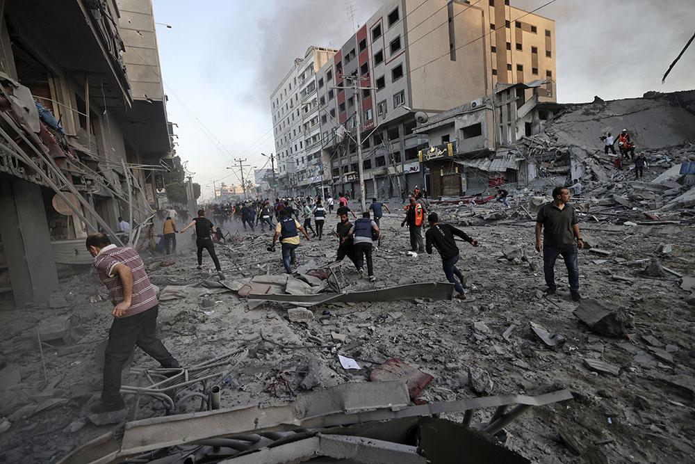 Rescuers and people gather amidst the rubble in front of Al-Sharouk tower that collapses after being hit by an Israeli air strike, in Gaza City, on May 12, 2021. 