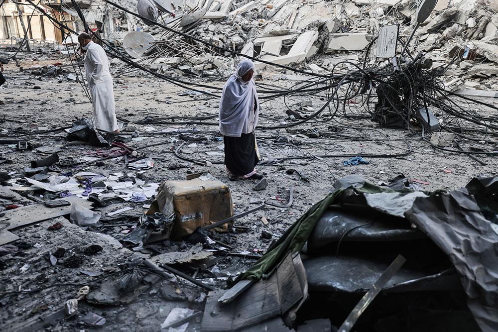 Palestinians walk after performing Eid al-Fitr prayers amidst debris near the al-Sharouk tower, which housed the bureau of the Al-Aqsa television channel in the Gaza Strip, after it was destroyed by an Israeli air strike, in Gaza City, on May 13, 2021.