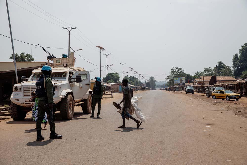 A picture of a man walking in front of military cars in Bangui.