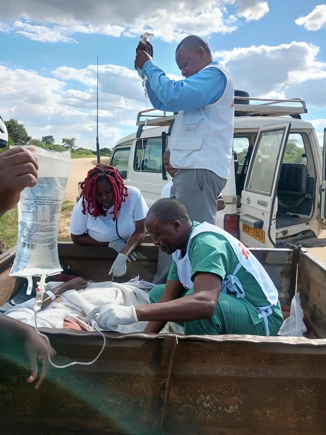 MSF staff treating a cholera patient in a scotch cart on the road side in Zimbabwe