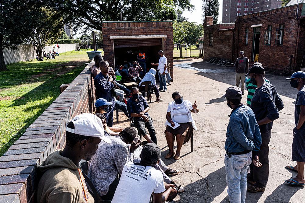 An MSF Health Promoter speaks with people about how to keep safe while they stay at a homeless shelter in Johannesburg, Sotuh Africa during the COVID-19 pandemic. 