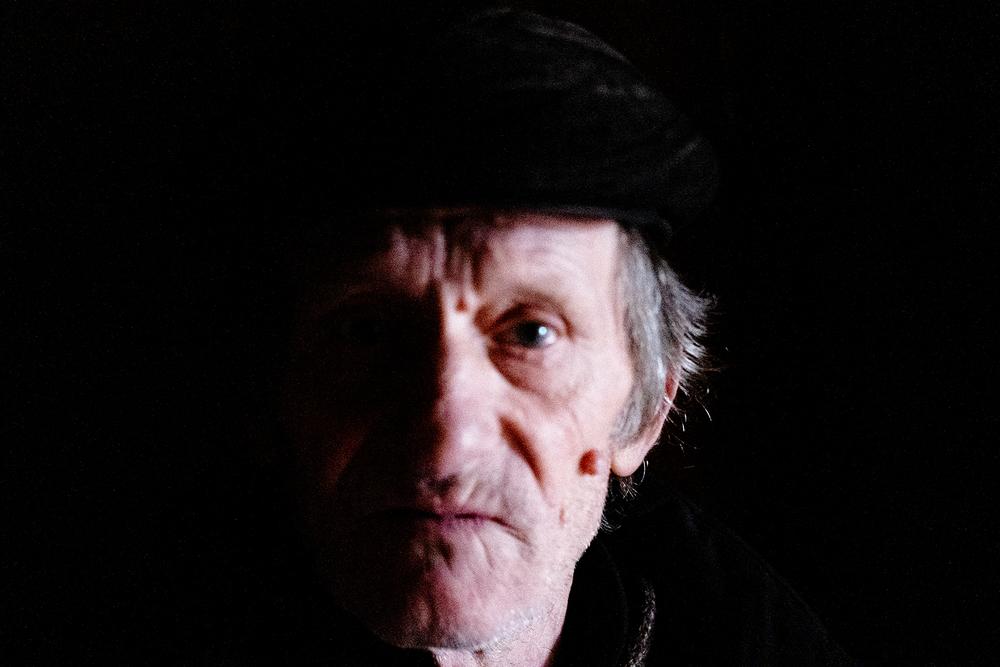 A man stares into the camera. Half his face is in shadow. He was photographed at an MSF mobile clinic set up to respond to epidemics and pandemics