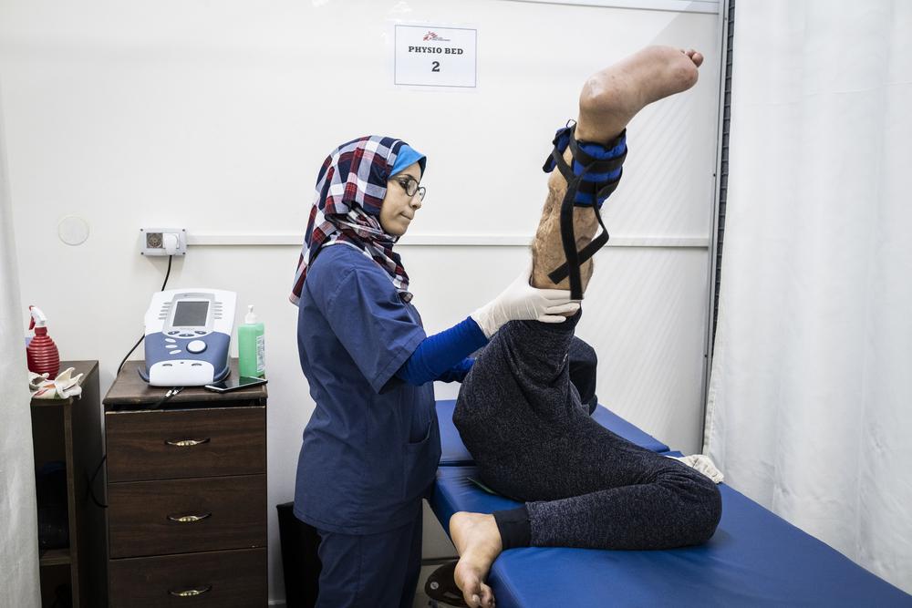 Sabrine Wadi, a physiotherapist working with MSF at Al Awda hospital in northern Gaza, assists a patient with his physiotherapy exercises.