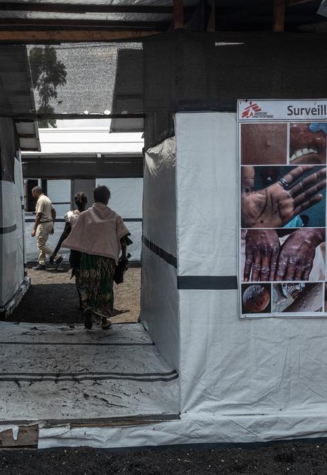 People enter a canvas and wood MSF mobile clinic.