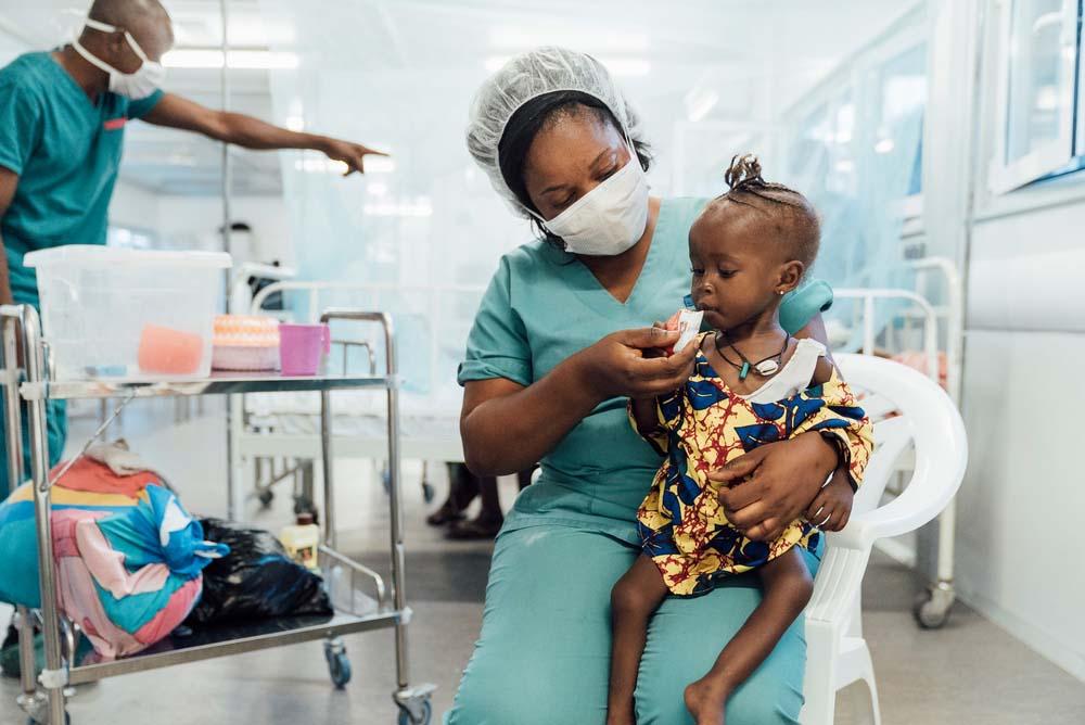 A picture of a child being fed by an MSF staff member in Kenama Hospital