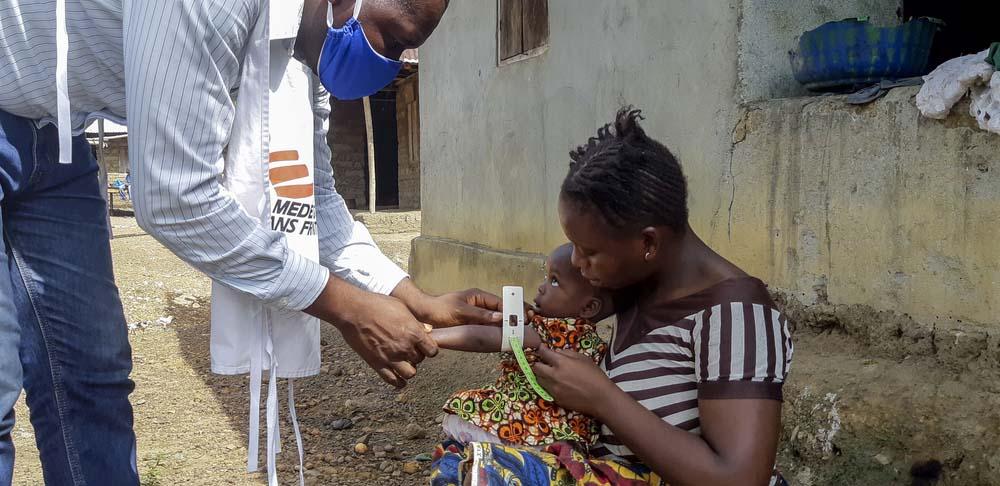 An MSF staff member measuring a child's arm for malnutrition